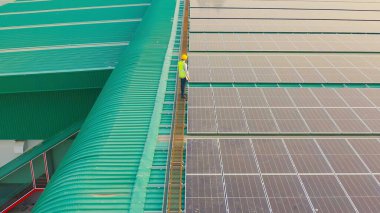 Fabrika endüstrisinde çatıda güneş panelleri ya da güneş pilleri olan mühendis ya da işçi, insanların havadan görünüşü. Enerji santrali, yenilenebilir enerji kaynağı. Elektrik enerjisi için eko teknoloji. Bakım