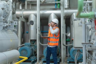 Bir mühendis ya da işçi, insanlar dizüstü bilgisayar kullanıyor, endüstri fabrikasında çalışıyor. Soğutma kulesi ya da soğutma kulesi. Sistem çalışma makinesi. Yoğunlaştırıcı Su Tedarik boru hatları. Havalandırma.