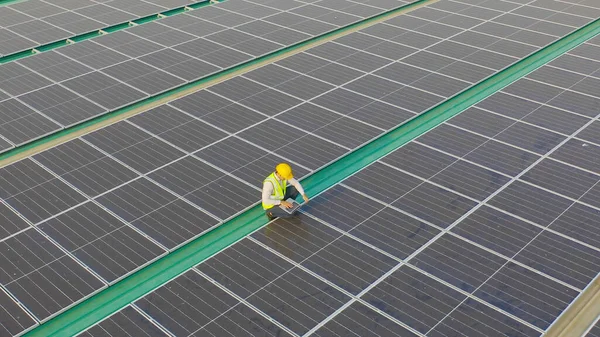 Aerial top view of engineer man or worker,people, with solar panels or solar cells on the roof in factory industry. Power plant, renewable energy source. Eco technology for electric power. Maintenance