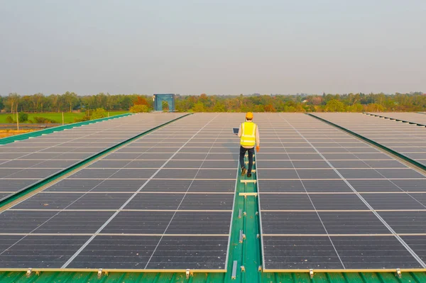 Aerial top view of engineer man or worker,people, with solar panels or solar cells on the roof in factory industry. Power plant, renewable energy source. Eco technology for electric power. Maintenance