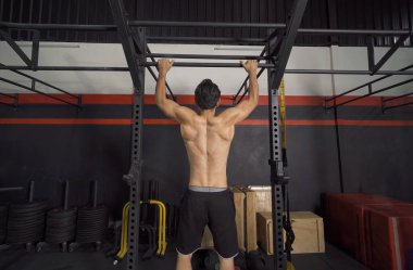 Ortadoğulu adam cesedi kaldırıyor, çubuğu asıyor, spor barına yanaşıyor. Jimnastik salonunda kas gücü antrenmanı. Spor malzemeleriyle içeride egzersiz yap. Atletik. İnsan yaşam tarzı.