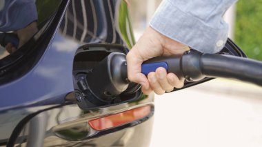 EV araba şarj aletini ya da elektrikli aracı fişe takıyorum. Benzin istasyonuna kablo bağlantısı, enerji arzı bataryası alternatif sürdürülebilir çevre dostane gelecekteki teknoloji enerjisi yeniliği şarj ediyor