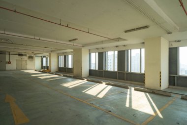 Otoparkların boş yeri. Penceresinden güneş ışığı görünen bir oda, iş merkezinin zemininde gölge efektleri, şehir merkezinde. Gökdelen ofis binaları.