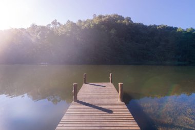 Pang Ung rezervuarında gölü ve orman ağaçları olan tahta köprü iskelesi, Mae Hong Son, Tayland. Yeşil çam, dağlar ve sudan yansıyan yansımalarla çevrili turistik bir yer..