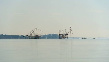 Günbatımında gölde ya da nehirde yerel balıkçı tuzağı olan bir yelkenli. Pak Pha, Phattalung, Tayland 'da doğa balıkçılığı ve balıkçılık aletleri. Hayvancılık çiftçiliği..