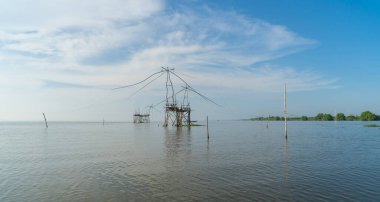 Günbatımında gölde ya da nehirde yerel balıkçı tuzağı olan bir yelkenli. Pak Pha, Phattalung, Tayland 'da doğa balıkçılığı ve balıkçılık aletleri. Hayvancılık çiftçiliği..