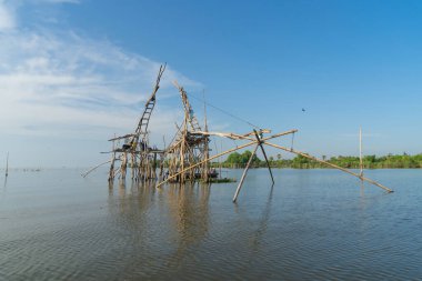 Günbatımında gölde ya da nehirde yerel balıkçı tuzağı olan bir yelkenli. Pak Pha, Phattalung, Tayland 'da doğa balıkçılığı ve balıkçılık aletleri. Hayvancılık çiftçiliği..