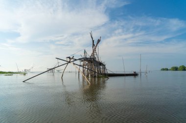 Günbatımında gölde ya da nehirde yerel balıkçı tuzağı olan bir yelkenli. Pak Pha, Phattalung, Tayland 'da doğa balıkçılığı ve balıkçılık aletleri. Hayvancılık çiftçiliği..
