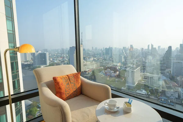 タイのバンコクシティスカイラインを望む客室には コーヒーカップ付きの椅子とテーブルがあります 金融街や高層ビルのオフィスビル ダウンタウンのスカイライン 都市部 リラックスエリア ライフスタイル — ストック写真