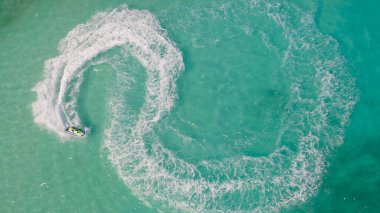 Jet ski ya da teknenin havadan görünüşü deniz okyanusu turkuaz suyuna şekil veriyor. Yaz mevsiminde maceraperest eğlence aktiviteleri. Yaşam biçimi