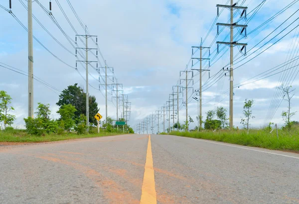 High voltage poles with street road. Power lines on utility tower and cable wires in energy electric technology, network, and industry concept. Generator pylon. Transmission and substation.