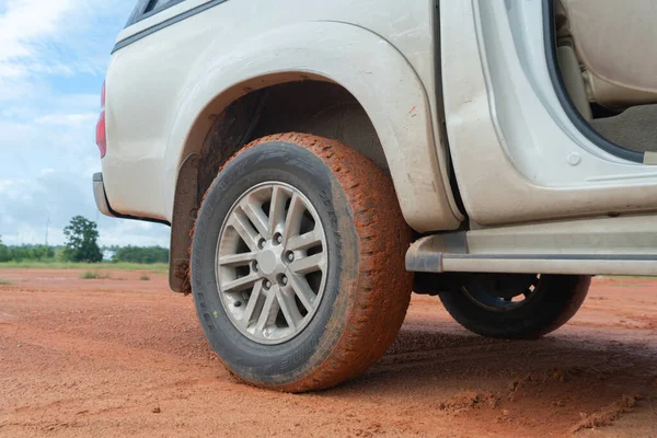 Muddy car tire wheel, red soil surface dirt road. Adventure in journey. Mud.