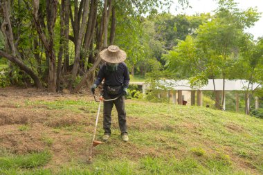 Bahçıvanın bahçedeki çim biçme makinesini kullanarak bahçe arazisindeki çim bitkisini kestiği yeri kapatın. Doğa. İnsanların yaşam tarzı. Bakım servisi.