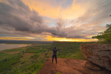 Tayland 'daki Ulusal Park' ta uçuruma tırmanan mutlu bir turist. Park manzaralı dağlık tepe manzarası. Günbatımında turist eğlencesi. Macera alanı. İnsan yaşam tarzı aktivitesi.