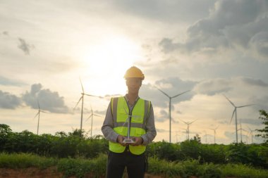 Asyalı yel değirmeni mühendisi, çalışan işçi, rüzgar türbinleri tarlasında ya da çiftlikte bir model tutan temiz enerji kaynağı. Elektrik için eko teknoloji. Endüstri doğası. İnsanlar