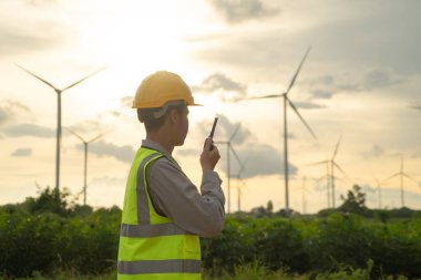 Asyalı yel değirmeni mühendisi portresi, rüzgar türbinleri tarlasında ya da çiftlikte çalışan işçi, yenilenebilir temiz enerji kaynağı. Elektrik enerjisi için eko teknoloji. Endüstri doğası. İnsanlar