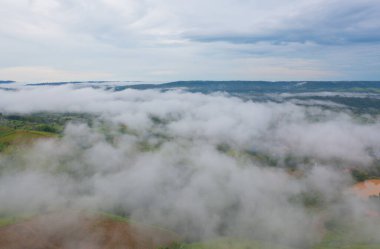 Gün batımında sisli orman ağaçlarının ve yeşil dağ tepelerinin havadan görünüşü. Doğa manzarası arka planı, Tayland.