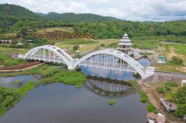 Tha Chomphu Beyaz Köprüsü, Lamphun, Tayland 'ın gölü ya da nehri, orman ağaçları ve yeşil dağ tepesi havadan görünüyor. Doğa manzarası. Turistik bölge simgesi.