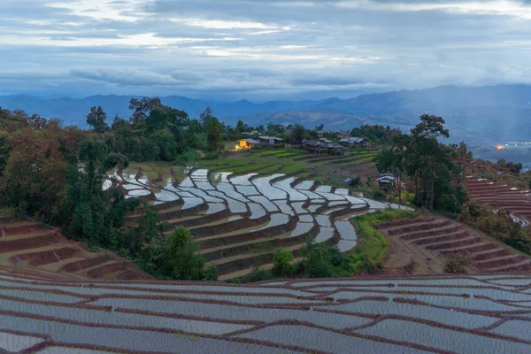 Paddy rice terraces with water reflection and rain storm, green agricultural fields in countryside, mountain hills valley, Pabongpieng, Chiang Mai, Thailand. Nature landscape. Crops harvest.