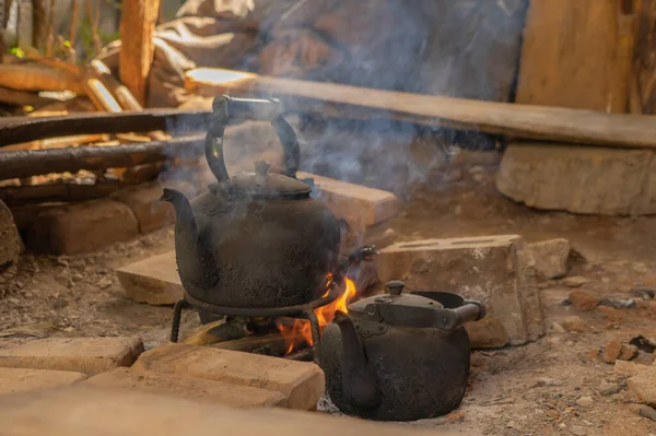Old teapot for boiling water by using traditional kettle and fire, water heater at wooden kitchen at local home. People lifestyle.