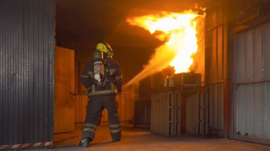 İtfaiyeci ya da üniformalı bir itfaiyeci sıcak ateşe karşı yangın hortumu ve konteynırdaki tehlikeli dumana karşı acil bir kaza kurtarma operasyonu kullanıyor. - İnsanlar. Kahraman