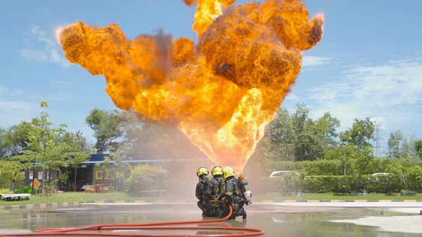 消防士や消防士のグループは コンテナ内の熱い燃焼火災や危険な煙 緊急事故救助に対して水の消防ホースを使用して均一で ヒーローチームワーク — ストック写真