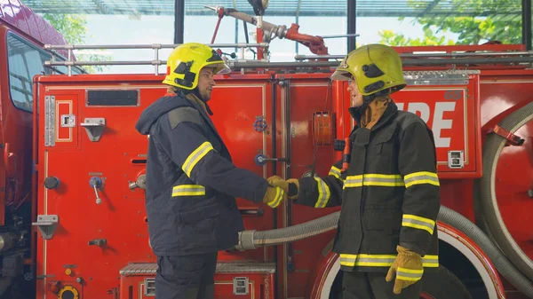 A successful group of caucasian firefighters or firemen team with uniform shaking hands, working on their career. An emergency accident rescue. People. Hero teamwork with a fire truck car. Service job
