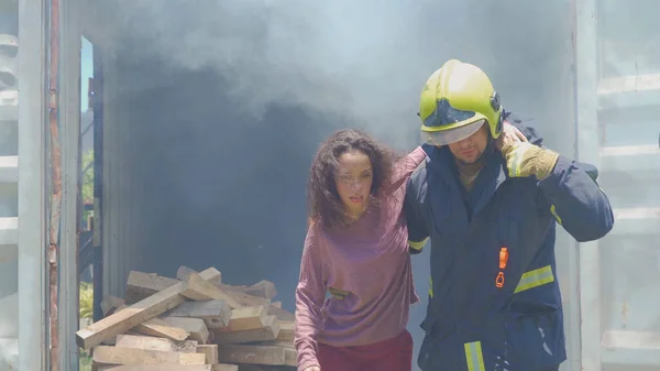 若い被害者の女性を助ける緊急救助チームは コンテナ内の熱い燃焼火災や危険な煙から彼女の命を救います 英雄だ 勤務先 — ストック写真