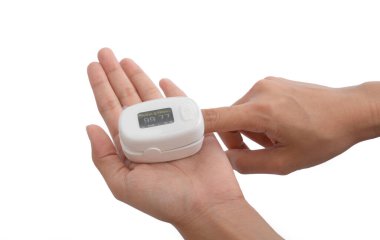 Nabız oksimetresi ya da kan oksijeni ölçme cihazı olan beyaz arka planda izole edilmiş bir el. Teşhis kendi kendini kontrol ediyor. Tıbbi ve sağlık ekipmanları. Coronavirüs covid-19 salgını.