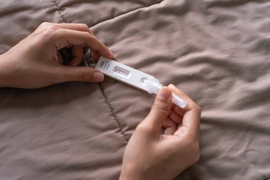 Evde el bir test fişeği tutuyor. COVID-19 AG hızlı test kitleri evdeki karantinada yataklarında. Antijen veya antikor testi. Virüs hastalığı sağlık kontrolü. Coronavirüs salgını.