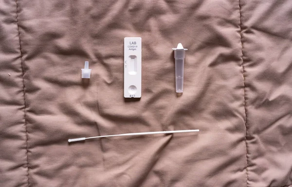 A set of COVID-19 rapid self test kits with medical equipment isolated on bed at home. Antigen or Antibody test. Virus disease healthcare check.