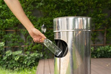 Boş plastik su şişesini paslanmaz çelik kutuya atmak. Çöp, çöp, çöp ya da çöp. Açık havada. Çevre. Geri Dönüşüm.