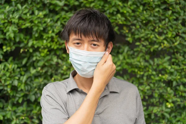 Portrait of ill young Asian man, person wearing a face mask for corona virus and health care concept in quarantine. Wearing medical mask.