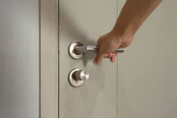A hand opening a door lock knob handle at home. Security. People lifestyle.