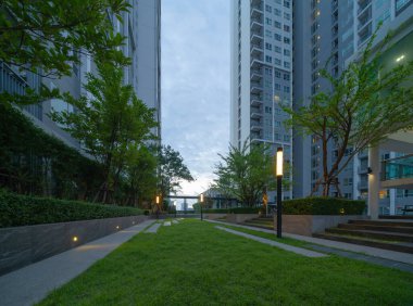 Gökyüzü parkı, özel çatı katı ya da otel bahçesi, ağaç, çimen tarlası ve mavi gökyüzü olan yüksek binalar..