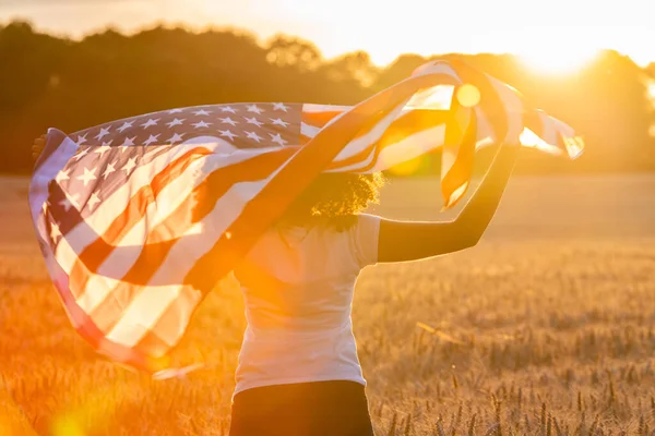 아프리카 미국인 소녀가 미국의 스타들에 밀이나 밭에서 햇살에 줄무늬 깃발을 — 스톡 사진