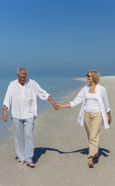 Gelukkige senior paar wandelen bedrijf handen tropisch strand — Stockfoto