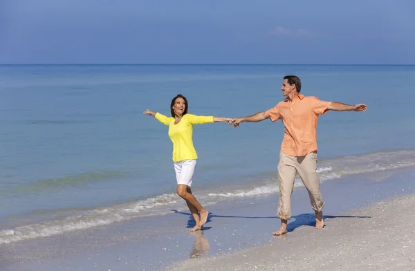 Ευτυχισμένο ζευγάρι τρέχει εκμετάλλευση τα χέρια σε μια παραλία — Φωτογραφία Αρχείου