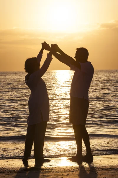Ανώτερος ζευγάρι, κρατώντας τα χέρια ηλιοβασίλεμα τροπική παραλία — Φωτογραφία Αρχείου