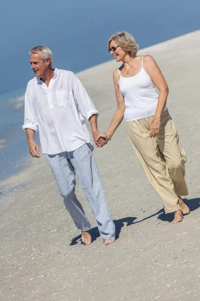 Pareja mayor feliz caminando con las manos en la playa tropical —  Fotos de Stock