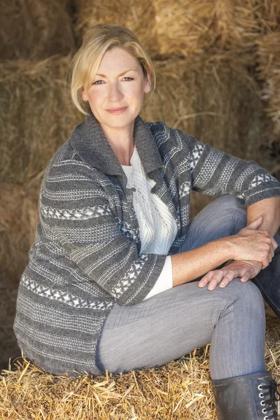 Blonde Frau mittleren Alters sitzt auf Heuballen — Stockfoto