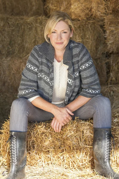 Blonde Frau mittleren Alters sitzt auf Heuballen — Stockfoto