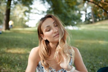 Meditasyon yapan, kapalı gözlü, yeşil çimlerin üzerinde güzel bir kız.