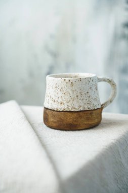 Beyaz bir bez üzerinde el yapımı bir seramik bardağın yakın plan fotoğrafı.