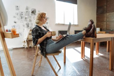 Sanat dersinde dizüstü bilgisayarda çalışan genç bir kadın.