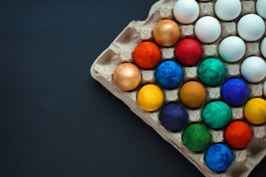 Siyah arka planda bir sürü renkli ve beyaz yumurta.