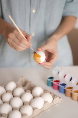 Kadın elleri Paskalya için yumurtayı altın boyayla boyarlar.
