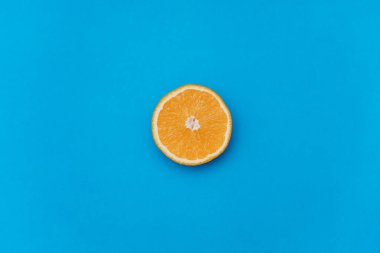 Mavi arka planda portakalın yarısı. Portakal tablonun ortasında. Boşluğu kopyala.