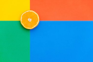 Portakalın yarısı çok renkli bir arka planın üst köşesinde. Uzayı kopyala Çoklu parlak renkler.