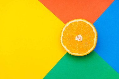 Renkli arka planda bir portakalın yakın plan fotoğrafı. Birden fazla parlak renk. Üst görünüm.
